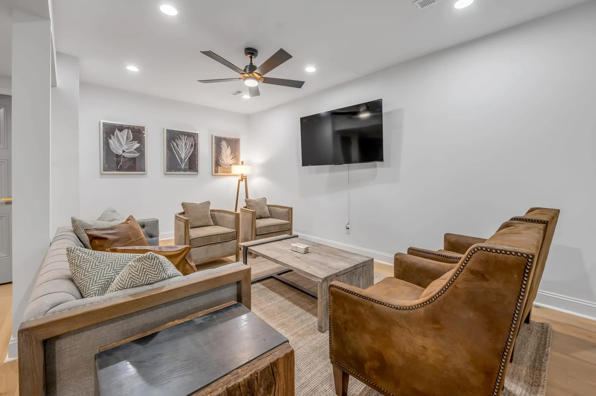 Sitting area at 300 Sherman with a sofa, two chairs, and a television on a white wall