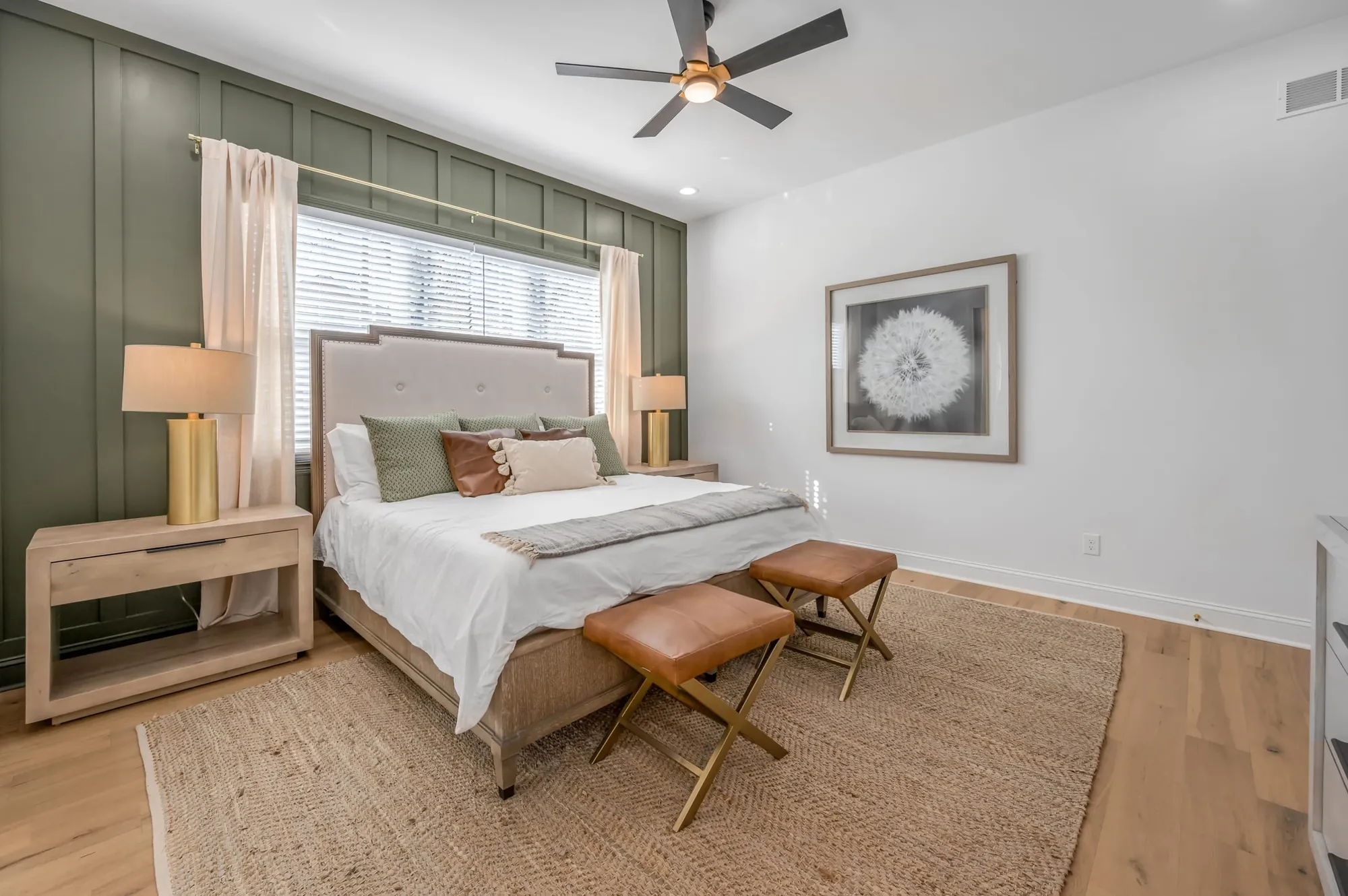 Primary bedroom at 300 Sherman with a made bed, a leather bench, and green walls