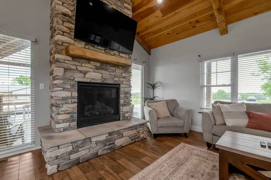 Baton Rouge House living room with a stone fireplace, a sofa, and two chairs