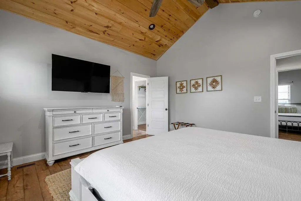 Bedroom at Baton Rouge House with a made bed, a long dresser, and a vaulted ceiling
